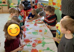 Przedszkolaki podczas malowania farbami na prześcieradle