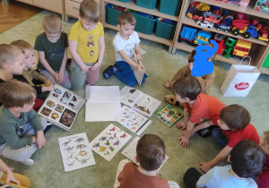 Dzieci oglądają ilustracje dinozaurów.