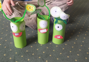 Dzieci wykonują ufoludki z zielonej rolki wykorzystując druciki kreatywne i kółka do origami.
