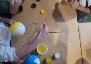 Dzieci malują planety podczas zajęć w księgarni.