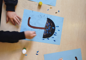 Dzieci wykonują pracę plastyczną- parasolki.