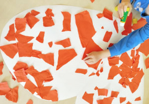 Dzieci wykonują pracę plastyczną techniką wydzieranki.