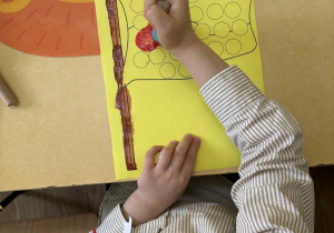 Mateusz podczas stemplowania farbami pracy plastycznej "Flaga Polski".