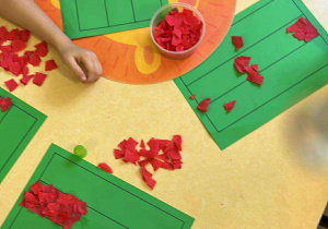Przyklejanie czerwonych kartek podczas wykonywania pracy plastycznej.