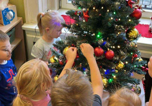Dzieci ubierają choinkę.