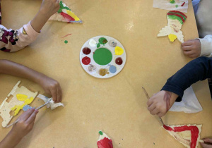 Przedszkolaki malują farbami filcowe ozdoby choinkowe.