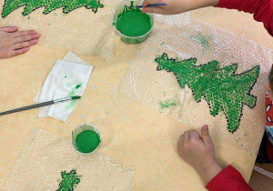 Malowanie farbami wzoru choinki na foli bąbelkowej.