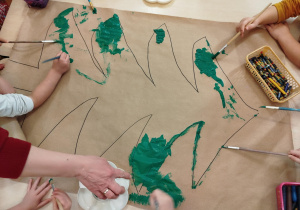 Kontur choinki malowany przez dzieci farbami.