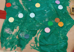 Pomalowana choinka z przyklejonymi kołami origami.