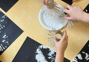 Przedszkolaki stemplują po czarnej kartce.