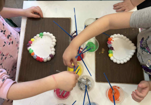 Przedszkolaki malują wybranymi farbami serduszka gipsowe.