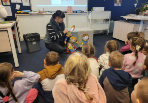 Dzieci słuchają opowiadania podczas zajęć w bibliotece.