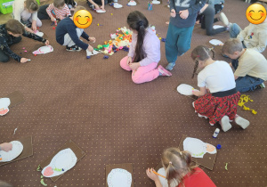 Dzieci ozdabiają korale dla babci z wykorzystaniem bibuły i kredek.