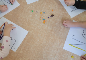 Dzieci ozdabiają szablon litery N z wykorzystaniem plasteliny.