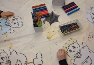 Dzieci ozdabiają pacynki z papieru podczas zajęć w bibliotece.