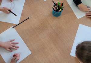 Dzieci rysują jeże na kartce.