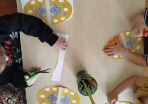 Dzieci wykonują wielkanocną dekorację.