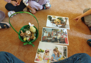 Dzieci oglądają koszyczek oraz zdjęcia przedstawiające wielkanocne tradycje.