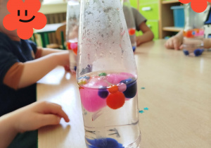 Dzieci tworzą butelki sensoryczne.