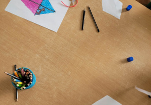 Dzieci przyklejają wstążki do swoich latawców.