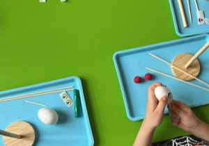 Dzieci wbijają wykałaczki w styropianowe jajka.