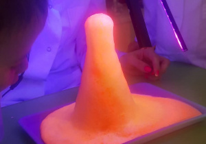 Dzieci obserwują fluorescencyjny wulkan.