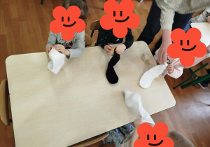 Dzieci wkładają kulkę ze sznurka do skarpetki.