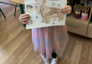 Nelia z wykonaną przez siebie kartą pracy - ćwiczenia grafomotoryczne.