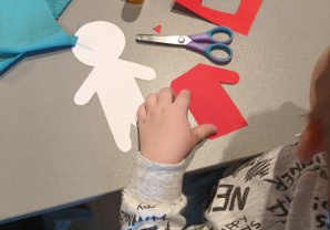 Dzieci z papieru wycinają ubranka dla lalek.