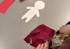 Dzieci wycinają z materiału ubranka dla swoich lalek.