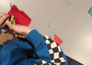 Dzieci wycinają z materiału ubranka dla swoich lalek.