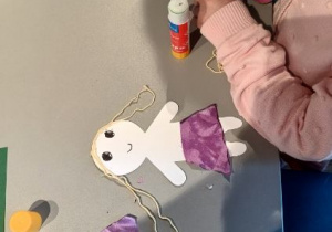 Dzieci naklejają włosy z włóczki.