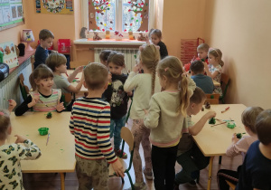 Dzieci podczas malowania szyszek farbami na zielono
