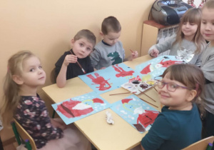 Dzieci malują farbami Świętego Mikołaja